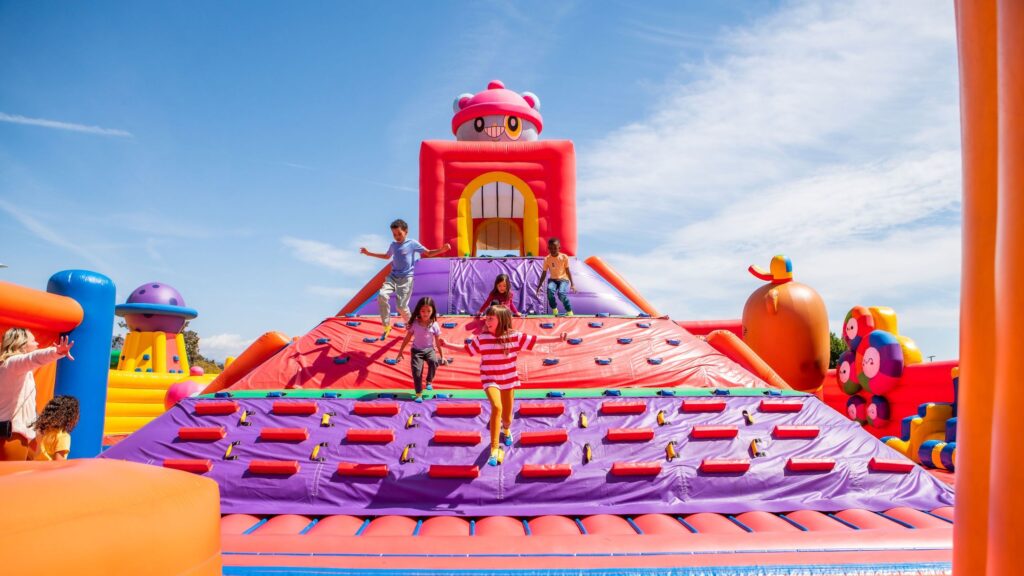 Niños jugando en parque inflable gigante de colores – alquiler de hinchables para eventos y fiestas infantiles en España

